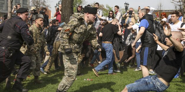 Mitten in einem Protest gegen Putin: Ein Mann in Uniform stößt einen Mann in kurzen Hosen zu Boden Mitten in einem Protest gegen Putin: Ein Mann in Uniform stößt einen Mann in kurzen Hosen zu Boden