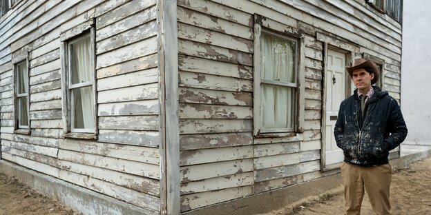 Ein Mann steht vor einem Holzhaus Ein Mann steht vor einem Holzhaus