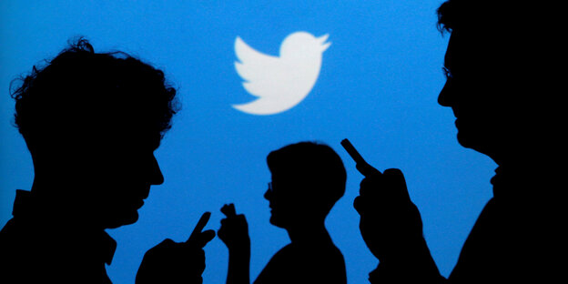 Das Twitter-Logo im Hintergrund, im Vordergrund sind Silhouetten von Menschen