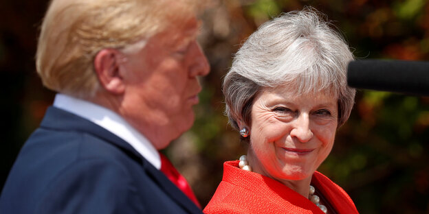 Theresa May schaut Donald Trump von der Seite an. Ihr Gesichtsausdruck ist kritisch-belustigt Theresa May schaut Donald Trump von der Seite an. Ihr Gesichtsausdruck ist kritisch-belustigt