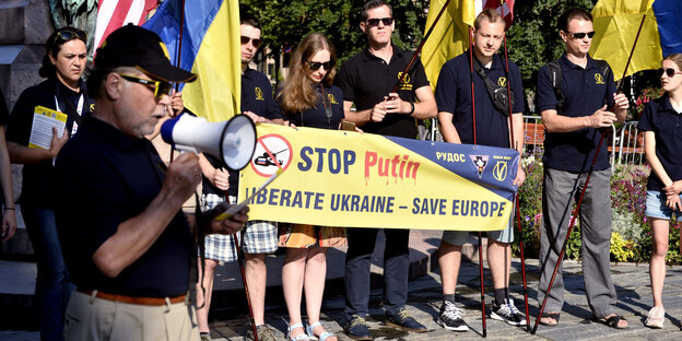 Demonstranten halten ein gelbes Transpi, auf dem Stop Putin steht Demonstranten halten ein gelbes Transpi, auf dem Stop Putin steht