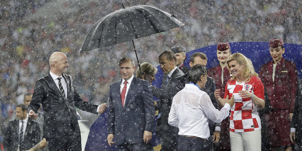 Putin unter einem Schirm, es regnet in Strömen Putin unter einem Schirm, es regnet in Strömen
