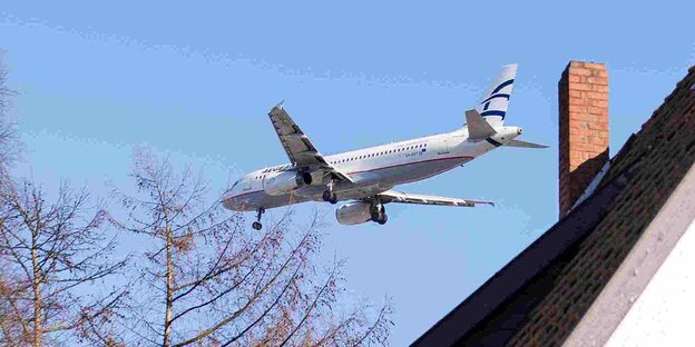 Ein Flugzeug fliegt über dem Dach eines Hauses. Ein Flugzeug fliegt über dem Dach eines Hauses.