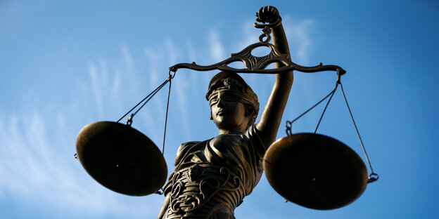 Die Statue einer Justizia mit Waagschale in der Hand vor blauem Himmel Die Statue einer Justizia mit Waagschale in der Hand vor blauem Himmel