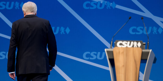 Horst Seehofer ist von hinten zu sehen, er wendet sich von einem Rednerpult ab Horst Seehofer ist von hinten zu sehen, er wendet sich von einem Rednerpult ab