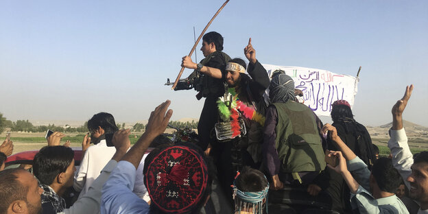 Taliban-Kämpfer winken, einer schwenkt eine weiße Fahne Taliban-Kämpfer winken, einer schwenkt eine weiße Fahne