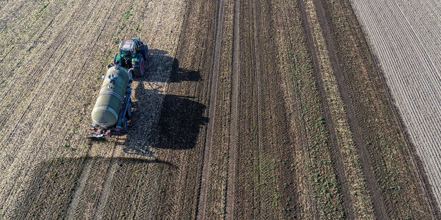 Ein Bauer versprüht mit seinem Traktor Gülle auf einem Acker Ein Bauer versprüht mit seinem Traktor Gülle auf einem Acker