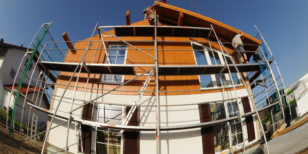 Arbeiter bauen am Dach eines Fertighauses Arbeiter bauen am Dach eines Fertighauses