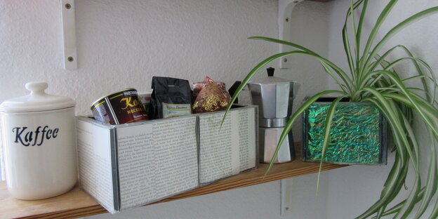 Ein Regal, darauf ein Gefäß, auf dem "Kaffee" steht, eine Espressokanne und zwei Boxen aus alten CDs gebaut Ein Regal, darauf ein Gefäß, auf dem "Kaffee" steht, eine Espressokanne und zwei Boxen aus alten CDs gebaut