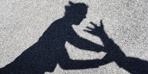 Ein Mann greift nach einer Frau, von beiden sind nur die Schatten zu sehen. Ein Mann greift nach einer Frau, von beiden sind nur die Schatten zu sehen.