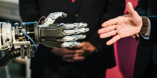 Eine menschliche und eine Roboterhand vor dem Handschlag Eine menschliche und eine Roboterhand vor dem Handschlag