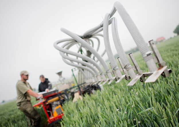 Eine Landwirtschaftsmaschine, die über mehrere Düsen Düngemittel auf einem Acker ausbringt.