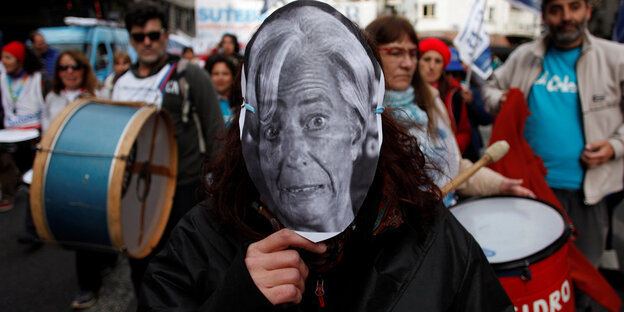 Ein Demonstrant mit einer Maske von Christine Lagarde Ein Demonstrant mit einer Maske von Christine Lagarde