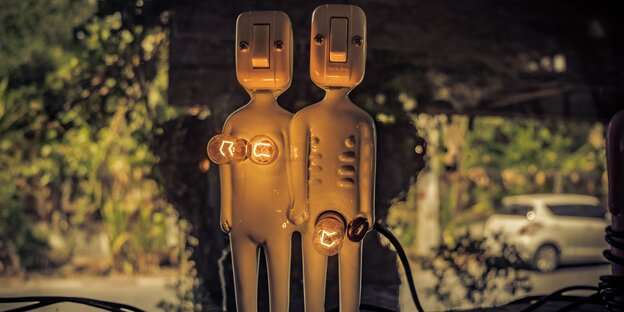 Figuren aus Keramik und Glühlampen. Die Glühlampen deuten bei einer Figur Brüste, bei der anderen einen Penis an Figuren aus Keramik und Glühlampen. Die Glühlampen deuten bei einer Figur Brüste, bei der anderen einen Penis an