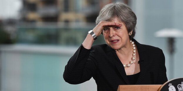Theresa May hält sich die Hand an die Stirn, um nicht geblendet zu werden Theresa May hält sich die Hand an die Stirn, um nicht geblendet zu werden