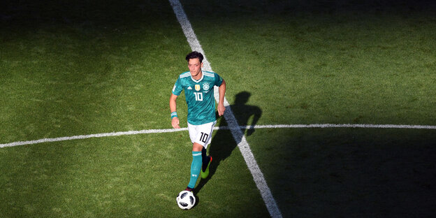 Der Fußballer Mesut Özil läuft traurig und konzentriert einem Fußball hinterher, er hat grünes Trikot an Der Fußballer Mesut Özil läuft traurig und konzentriert einem Fußball hinterher, er hat grünes Trikot an