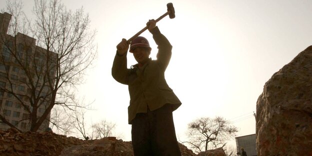 Ein Mensch zerschlägt etwas mit einem Hammer Ein Mensch zerschlägt etwas mit einem Hammer