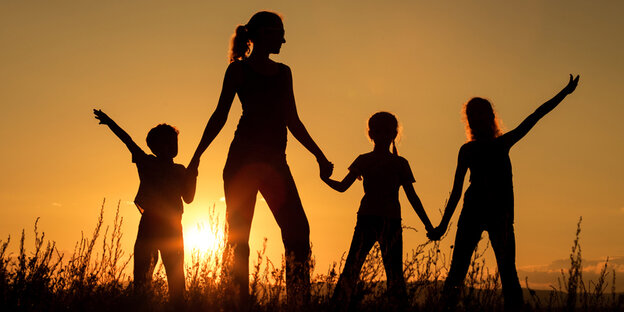 Eine Erwachsene und drei Kinder im Gegenlicht Eine Erwachsene und drei Kinder im Gegenlicht