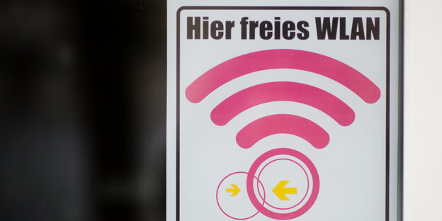 An einer Fensterscheibe klebt ein Zettel. Auf dem Zettel steht: „Hier freies WLAN“ An einer Fensterscheibe klebt ein Zettel. Auf dem Zettel steht: „Hier freies WLAN“