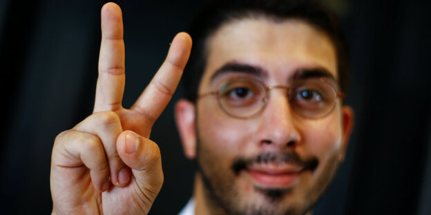 Ali Can hält die Hand zum Peace-Zeichen in die Kamera Ali Can hält die Hand zum Peace-Zeichen in die Kamera