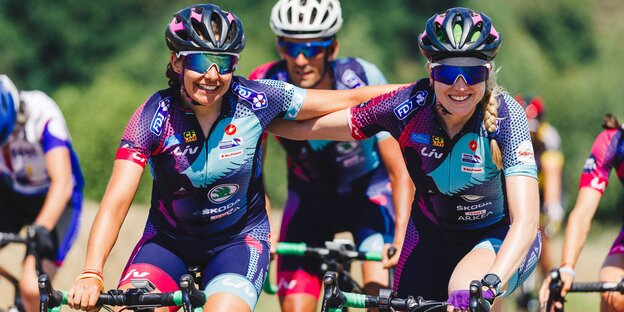 Zwei Radfahrerin legen sich die Hände auf die Schultern Zwei Radfahrerin legen sich die Hände auf die Schultern
