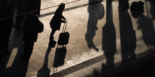 Silhouette einer Frau mit Rollkoffer Silhouette einer Frau mit Rollkoffer