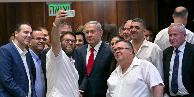 Israelischer Regierungschef Benjamin Netanjahu umgeben von knapp einem Dutzend Abgordneter der Koalitionsparteien, die ein Selfie aufnehmen Israelischer Regierungschef Benjamin Netanjahu umgeben von knapp einem Dutzend Abgordneter der Koalitionsparteien, die ein Selfie aufnehmen