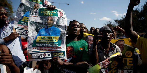 Unterstützer der ZANU-PF-Partei mit Wahlplakaten Unterstützer der ZANU-PF-Partei mit Wahlplakaten