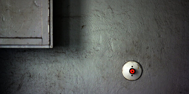 ein Lichtschalter mit rotem Knopf an einer grauen Wand ein Lichtschalter mit rotem Knopf an einer grauen Wand