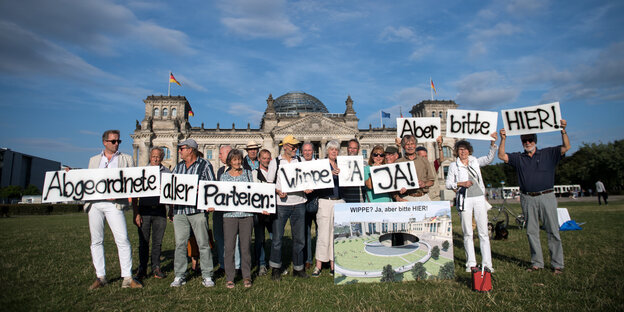 Menschen stehen mit Plakaten vor dem deutschen Bundestag. Sie demonstrieren für das Denkmal für die deutsche Einheit Menschen stehen mit Plakaten vor dem deutschen Bundestag. Sie demonstrieren für das Denkmal für die deutsche Einheit