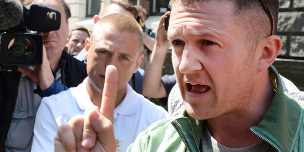 Der britische Rechtsextremist Tommy Robinson hetzt mit erhobenem Zeigefinger vor einer Kamera. Der britische Rechtsextremist Tommy Robinson hetzt mit erhobenem Zeigefinger vor einer Kamera.