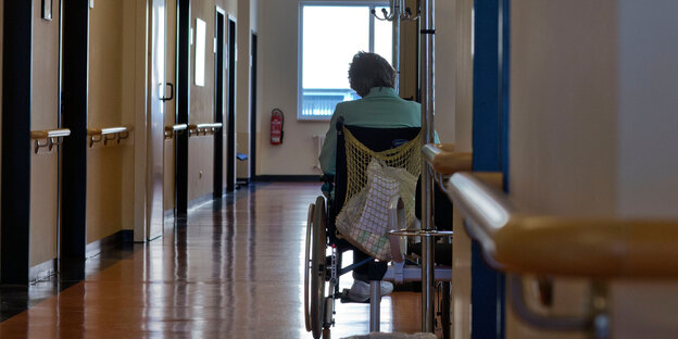 Eine Patientin im Rollstuhl steht alleine auf einem Krankenhausflur. Eine Patientin im Rollstuhl steht alleine auf einem Krankenhausflur.