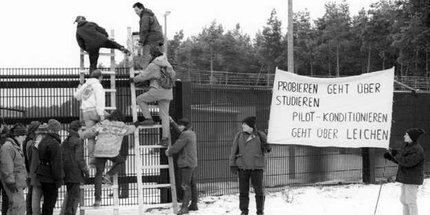 Atomkraftgegner klettern mit Leitern über einen Zaun. Atomkraftgegner klettern mit Leitern über einen Zaun.