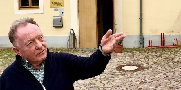 Ein Mann zeigt auf ein Gebäude in dem sich sein „Hofbuchladen" befindet Ein Mann zeigt auf ein Gebäude in dem sich sein „Hofbuchladen" befindet