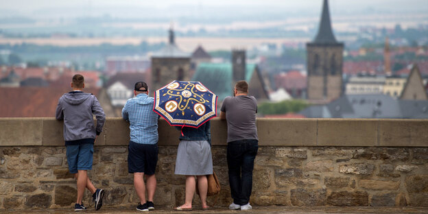 Vier Menschen gucken über ein Mäuerchen auf Erfurt hinunter Vier Menschen gucken über ein Mäuerchen auf Erfurt hinunter