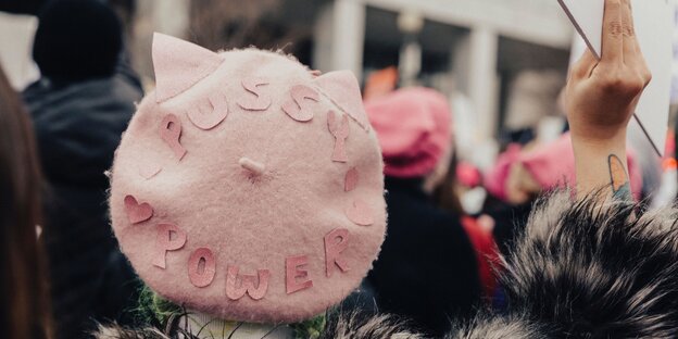 Eine Frau trägt eine rosa Mütze, auf der „Pussy Power“ steht Eine Frau trägt eine rosa Mütze, auf der „Pussy Power“ steht