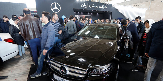 Besucher einer Automesse begutachten einen Mercedes Besucher einer Automesse begutachten einen Mercedes