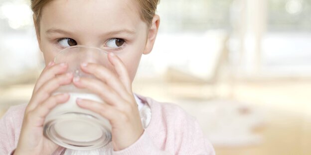 ein Kind hält ein Glas voll Milch an seinen Mund und trinkt ein Kind hält ein Glas voll Milch an seinen Mund und trinkt