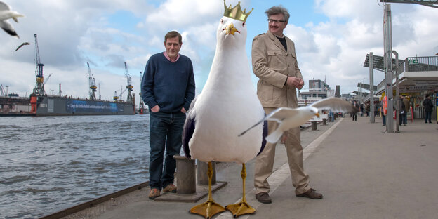 Andreas Dorau und Gereon Klug stehen mit einer Riesenmöwe mit Krone am Hamburger Hafen (Fotomontage) Andreas Dorau und Gereon Klug stehen mit einer Riesenmöwe mit Krone am Hamburger Hafen (Fotomontage)