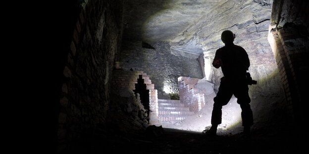 Ein Mann steht vor einem zugemauerten Aufgang in den Gertrudenberger Höhlen. Ein Mann steht vor einem zugemauerten Aufgang in den Gertrudenberger Höhlen.