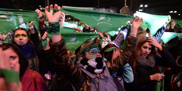 Frauen halten grüne Halstücher in die Luft Frauen halten grüne Halstücher in die Luft