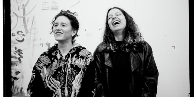 Zwei Frauen sitzen nebeneinander und lachen herzlich Zwei Frauen sitzen nebeneinander und lachen herzlich
