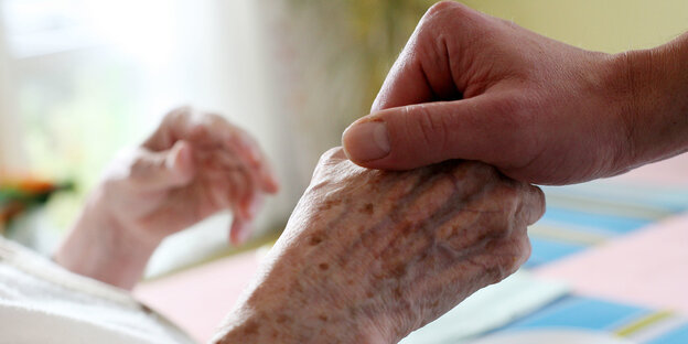 Pfleger hält Hand von Patientin im Bett Pfleger hält Hand von Patientin im Bett