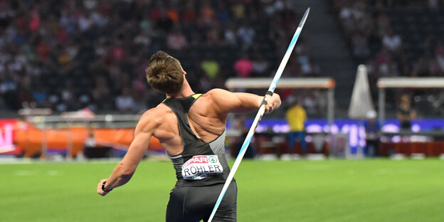 Ein Sportler holt weit aus, um einen Speer zu werfen Ein Sportler holt weit aus, um einen Speer zu werfen