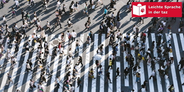 Sehr viele Menschen gehen an einem Zebrastreifen über die Straße