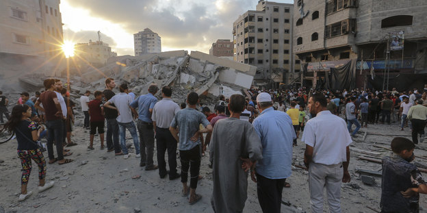 Palästinenser stehen in den Trümmern eines zerstörten Gebäudes