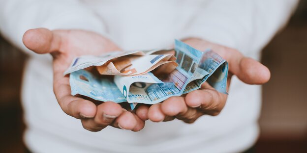 Euro-Banknoten liegen in zwei Händen Euro-Banknoten liegen in zwei Händen