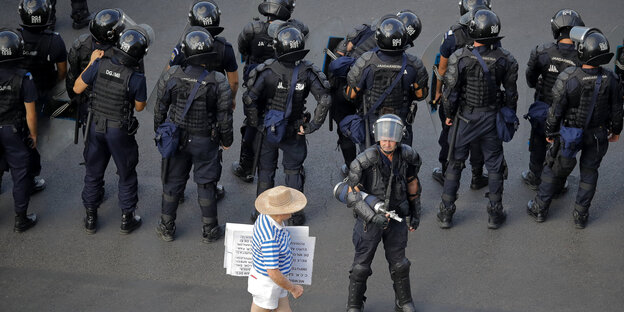 Ein einzelner Demonstrant vor einer Gruppe von Polizisten Ein einzelner Demonstrant vor einer Gruppe von Polizisten