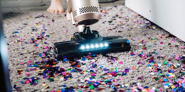 Ein Staubsauger saugt Glitzerkonfetti auf Ein Staubsauger saugt Glitzerkonfetti auf