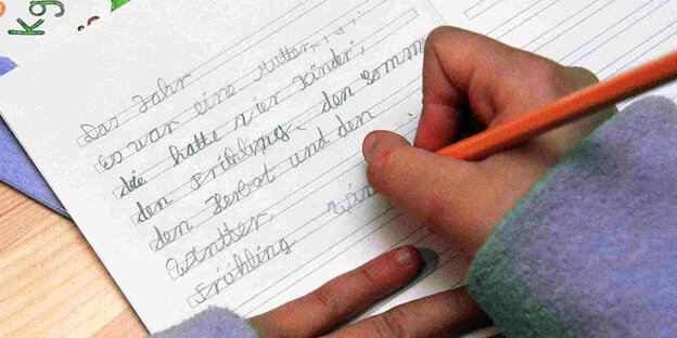 Ein Kind schreibt einen Text in ein Schulheft. Ein Kind schreibt einen Text in ein Schulheft.
